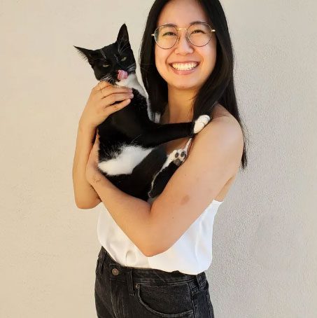 lily au dvm smiling and holding black and white cat